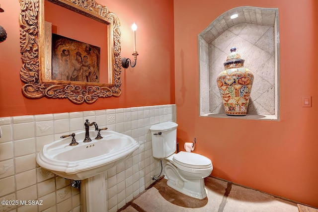 bathroom featuring toilet, a wainscoted wall, and tile walls