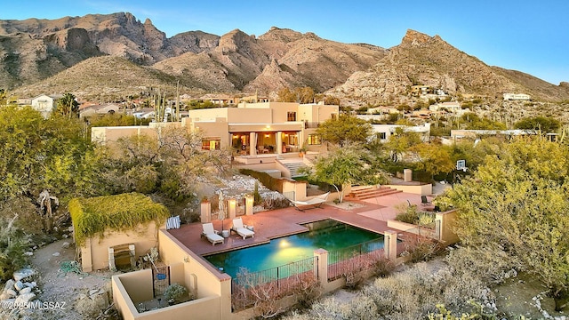 rear view of property featuring stucco siding, a mountain view, an outdoor pool, and a patio