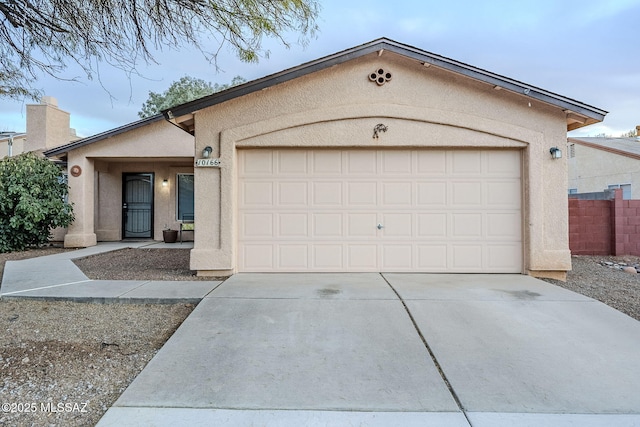 ranch-style house with a garage, concrete driveway, and stucco siding