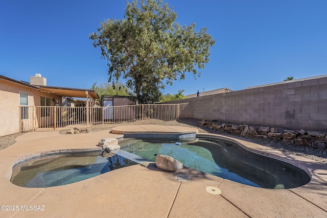 view of swimming pool featuring a patio area, a fenced backyard, a pool with connected hot tub, and an outbuilding