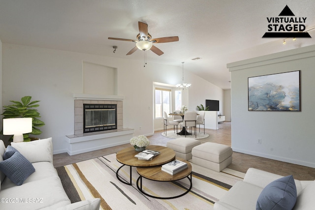 living area featuring vaulted ceiling, a tiled fireplace, visible vents, and baseboards