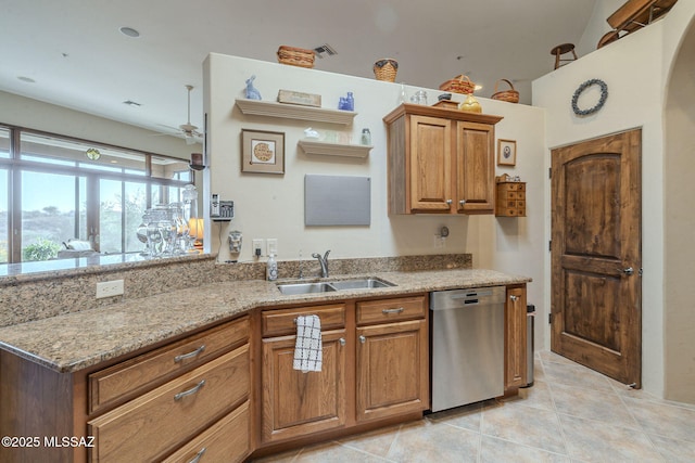 kitchen featuring arched walkways, brown cabinetry, a sink, light stone countertops, and dishwasher