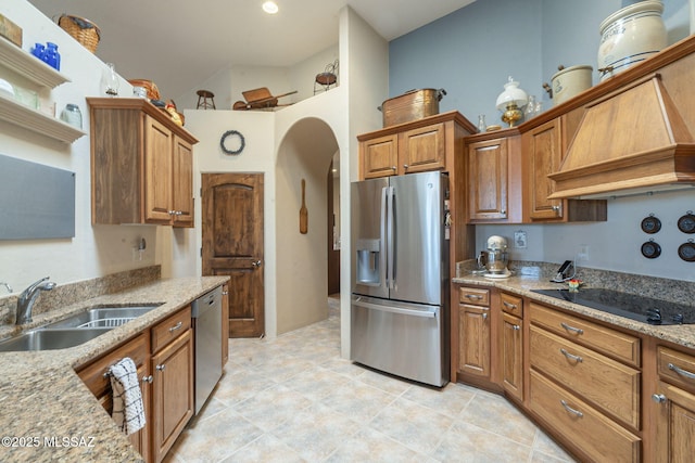 kitchen with brown cabinets, appliances with stainless steel finishes, arched walkways, and a sink