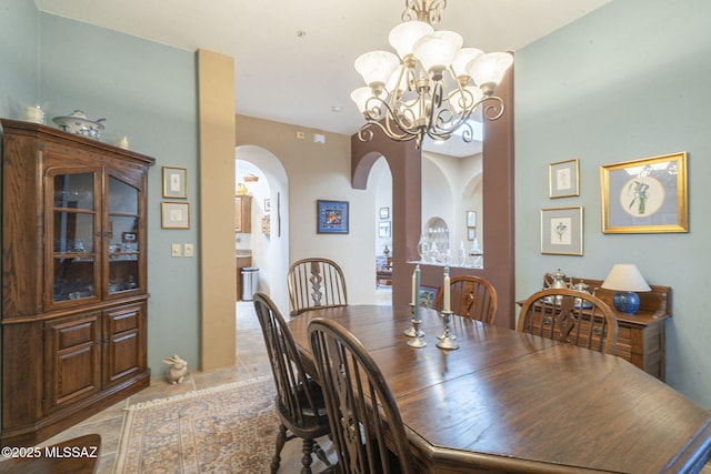 dining space featuring light tile patterned floors, arched walkways, and a notable chandelier