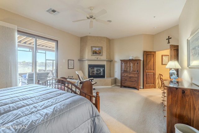 carpeted bedroom with a large fireplace, access to outside, visible vents, and ceiling fan