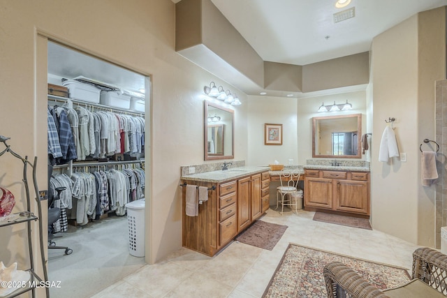 bathroom with two vanities, a sink, and a spacious closet