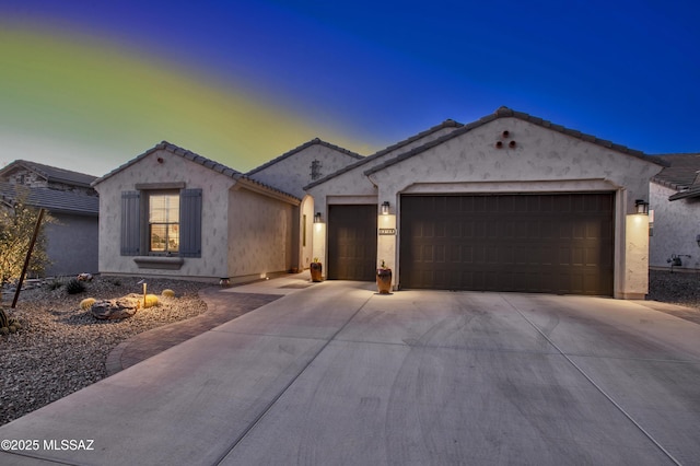 mediterranean / spanish-style home with an attached garage, driveway, a tile roof, and stucco siding