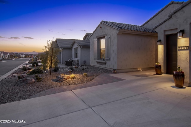 view of side of property featuring a patio area, a tile roof, and stucco siding