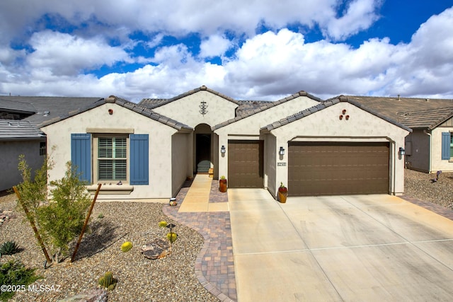 view of front of property featuring a garage, a tiled roof, concrete driveway, and stucco siding