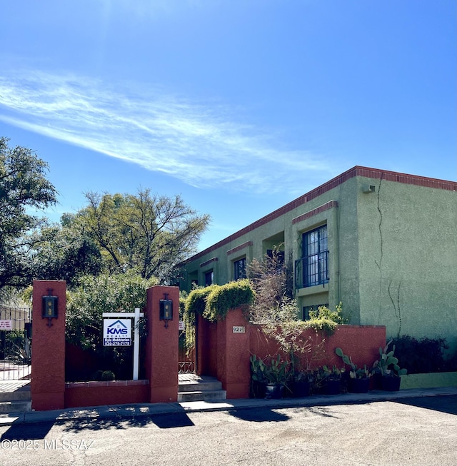 view of front of house with fence, a gate, and stucco siding