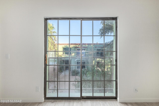 doorway to outside featuring baseboards and wood finished floors