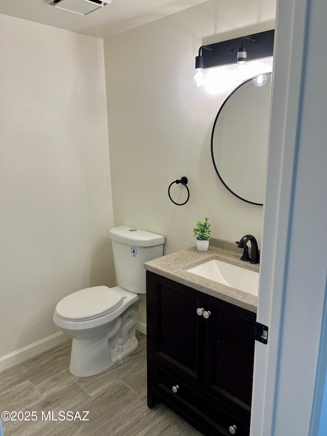 bathroom with baseboards, vanity, toilet, and wood finished floors