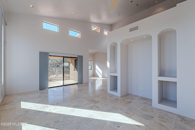 spare room featuring a towering ceiling, plenty of natural light, visible vents, and recessed lighting