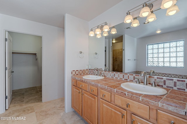 bathroom featuring a spacious closet, visible vents, decorative backsplash, and a sink