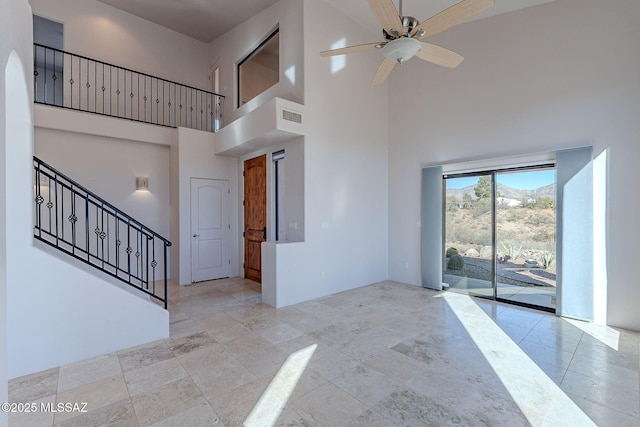 entrance foyer featuring a towering ceiling, stairs, visible vents, and a ceiling fan