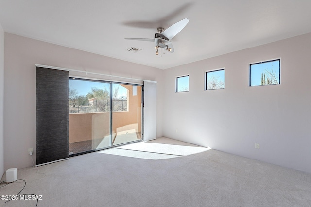 empty room with a ceiling fan, light colored carpet, and visible vents