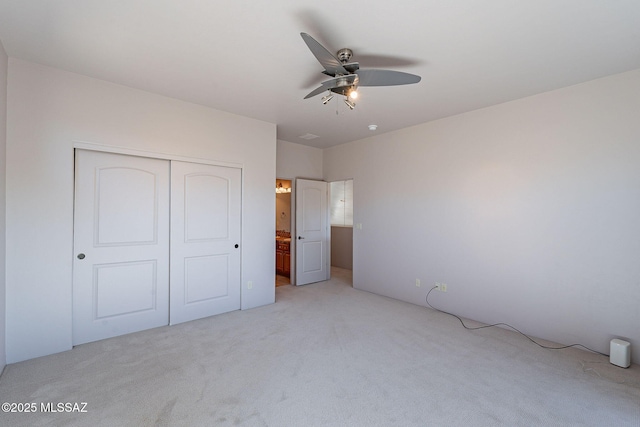 unfurnished bedroom featuring light carpet, ceiling fan, and a closet