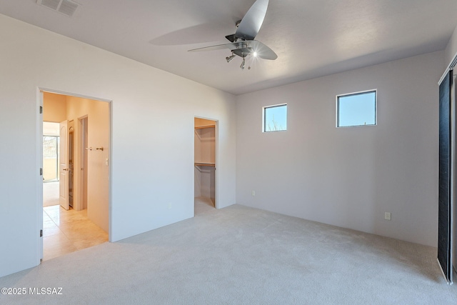 unfurnished bedroom with a ceiling fan, visible vents, light carpet, and a spacious closet