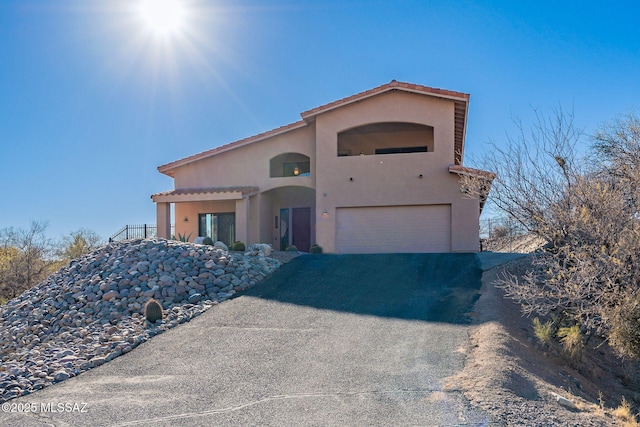 view of front of home featuring an attached garage, aphalt driveway, and stucco siding