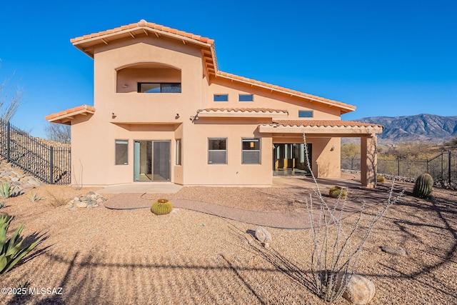 back of property with a tiled roof, fence, a patio area, a mountain view, and stucco siding