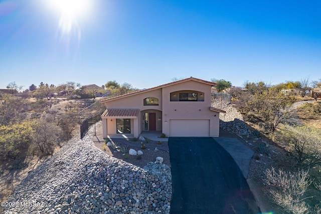 mediterranean / spanish home featuring driveway, an attached garage, a tile roof, and stucco siding