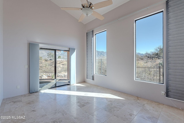 unfurnished room with ceiling fan, high vaulted ceiling, and a mountain view