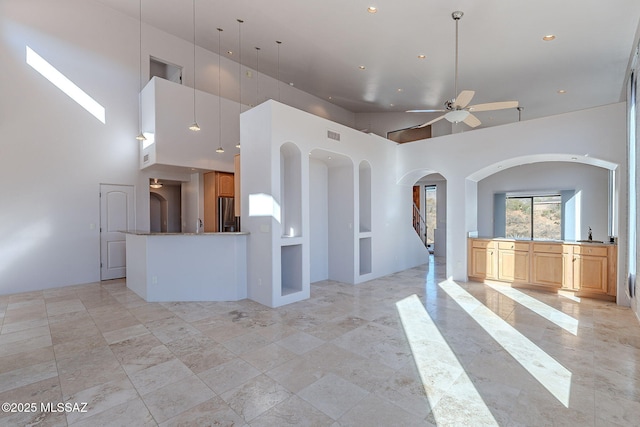 kitchen with open floor plan, a high ceiling, stainless steel fridge, and a ceiling fan