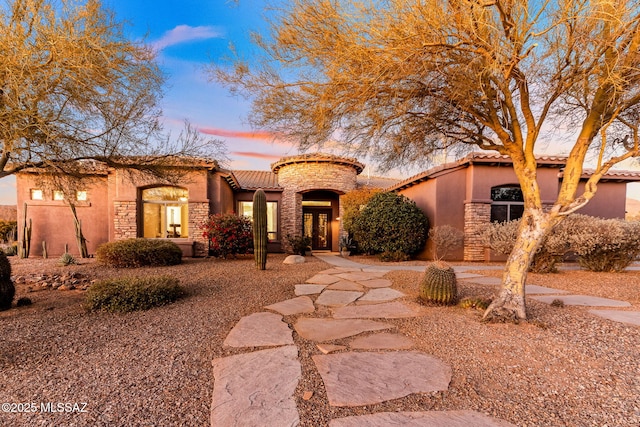 mediterranean / spanish-style home with stone siding, stucco siding, and a tiled roof