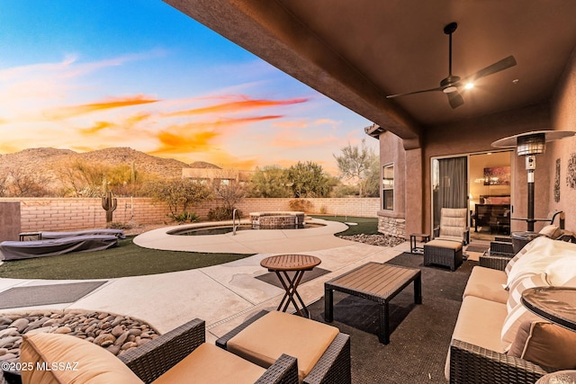 view of patio with a fenced backyard, ceiling fan, an outdoor living space, and a mountain view