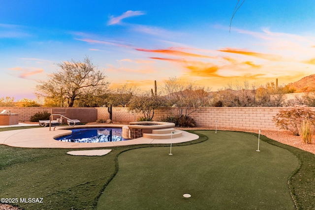 pool at dusk featuring a pool with connected hot tub, a fenced backyard, and a patio