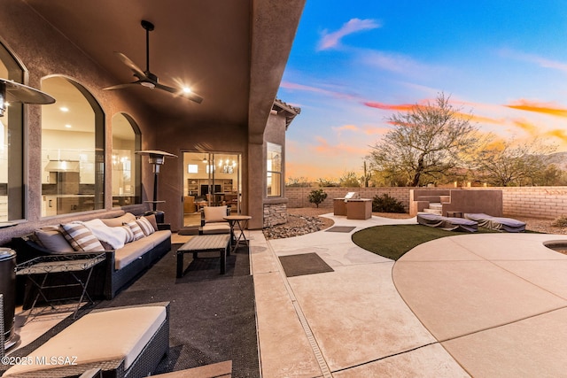 patio terrace at dusk featuring ceiling fan, fence, and an outdoor hangout area