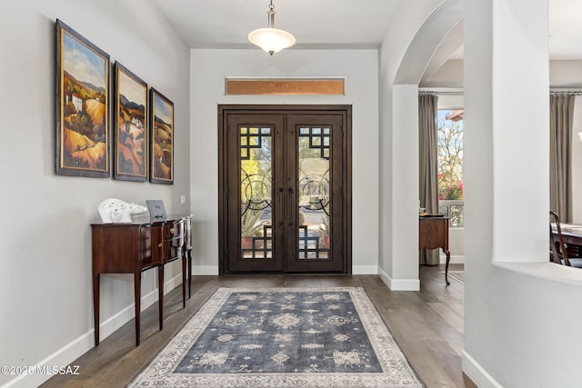 foyer featuring arched walkways, french doors, a healthy amount of sunlight, and wood finished floors