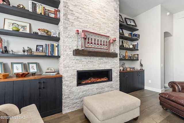 living room featuring baseboards, a fireplace, arched walkways, and hardwood / wood-style floors