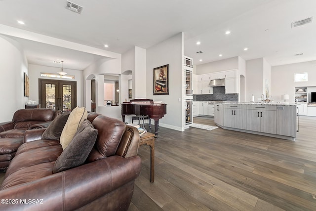 living room featuring arched walkways, dark wood-style flooring, visible vents, and recessed lighting