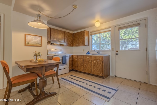 kitchen with brown cabinets, decorative light fixtures, white electric stove, light countertops, and under cabinet range hood