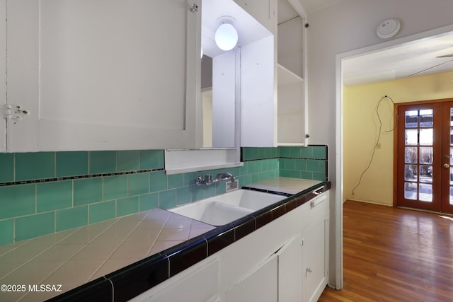 kitchen featuring french doors, tile counters, decorative backsplash, white cabinets, and a sink