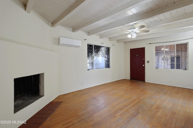 unfurnished living room with wood finished floors, beamed ceiling, a wall unit AC, and a fireplace