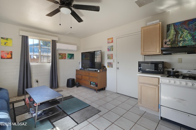 interior space featuring light countertops, an AC wall unit, light brown cabinetry, black microwave, and gas range gas stove