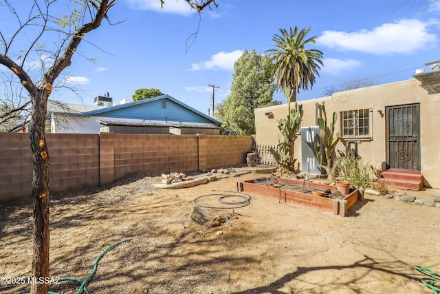 view of yard with entry steps, a vegetable garden, and fence