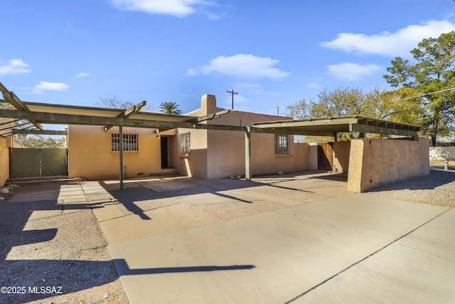 back of property featuring a carport, fence, and stucco siding