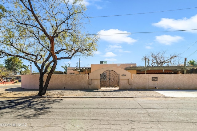 adobe home featuring a fenced front yard, a gate, and stucco siding