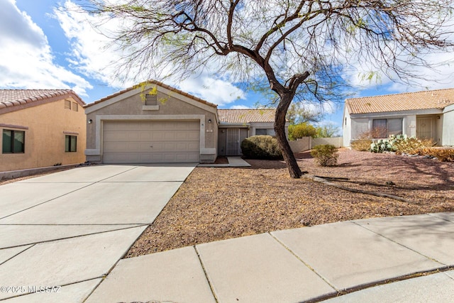 single story home with concrete driveway, a tile roof, an attached garage, and stucco siding