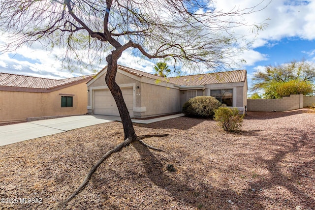 back of house with a garage, fence, driveway, and stucco siding