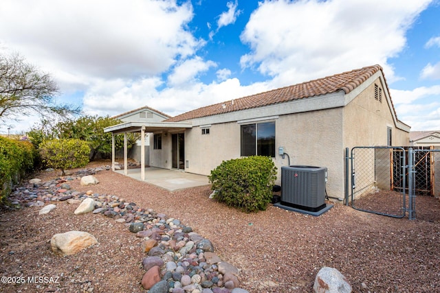 rear view of property featuring central AC unit, a patio, a gate, fence, and stucco siding