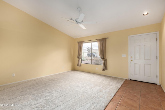 spare room featuring ceiling fan, lofted ceiling, light tile patterned flooring, light carpet, and baseboards