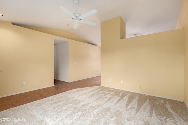 carpeted empty room featuring ceiling fan, tile patterned flooring, and vaulted ceiling