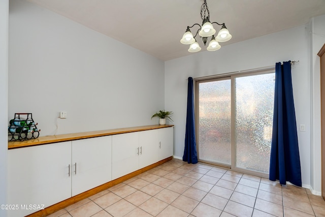 empty room with baseboards, light tile patterned flooring, and an inviting chandelier