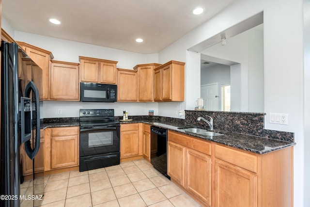 kitchen with recessed lighting, light tile patterned flooring, a sink, dark stone countertops, and black appliances