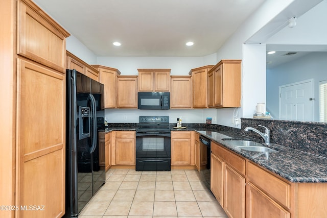 kitchen featuring light tile patterned floors, dark stone countertops, a peninsula, black appliances, and a sink