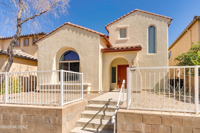 mediterranean / spanish home featuring a tiled roof, fence, and stucco siding